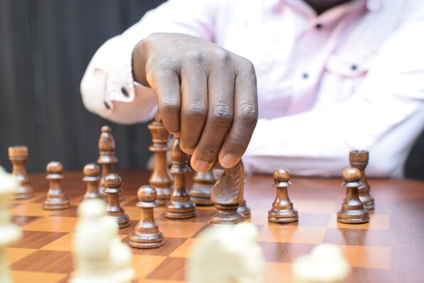 A hand placing a chess piece on a chessboard. - Toa Hub Hotel (Port Harcourt)