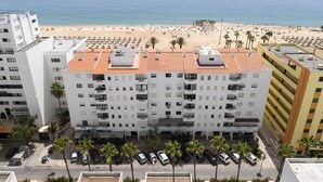 A multi-story hotel with a rooftop terrace, a parking lot, and a view of a beach. - Gira Sol by Hdproperties (Quarteira)