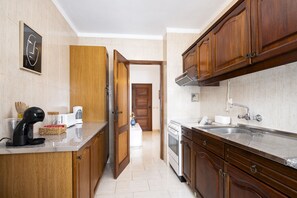 A modern kitchen with wooden cabinets, a built-in oven, and a stainless steel sink. - Gira Sol by Hdproperties (Quarteira)