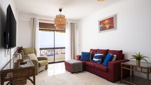 A modern living room with a red sofa, a television, and a balcony with a view. - Gira Sol by Hdproperties (Quarteira)