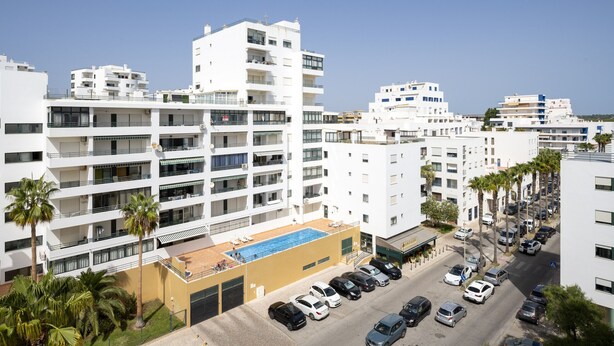 A multi-story hotel with balconies, a swimming pool, and a parking area. - Gira Sol by Hdproperties (Quarteira)