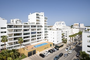 Un hotel de varios pisos con balcones, piscina y zona de estacionamiento.