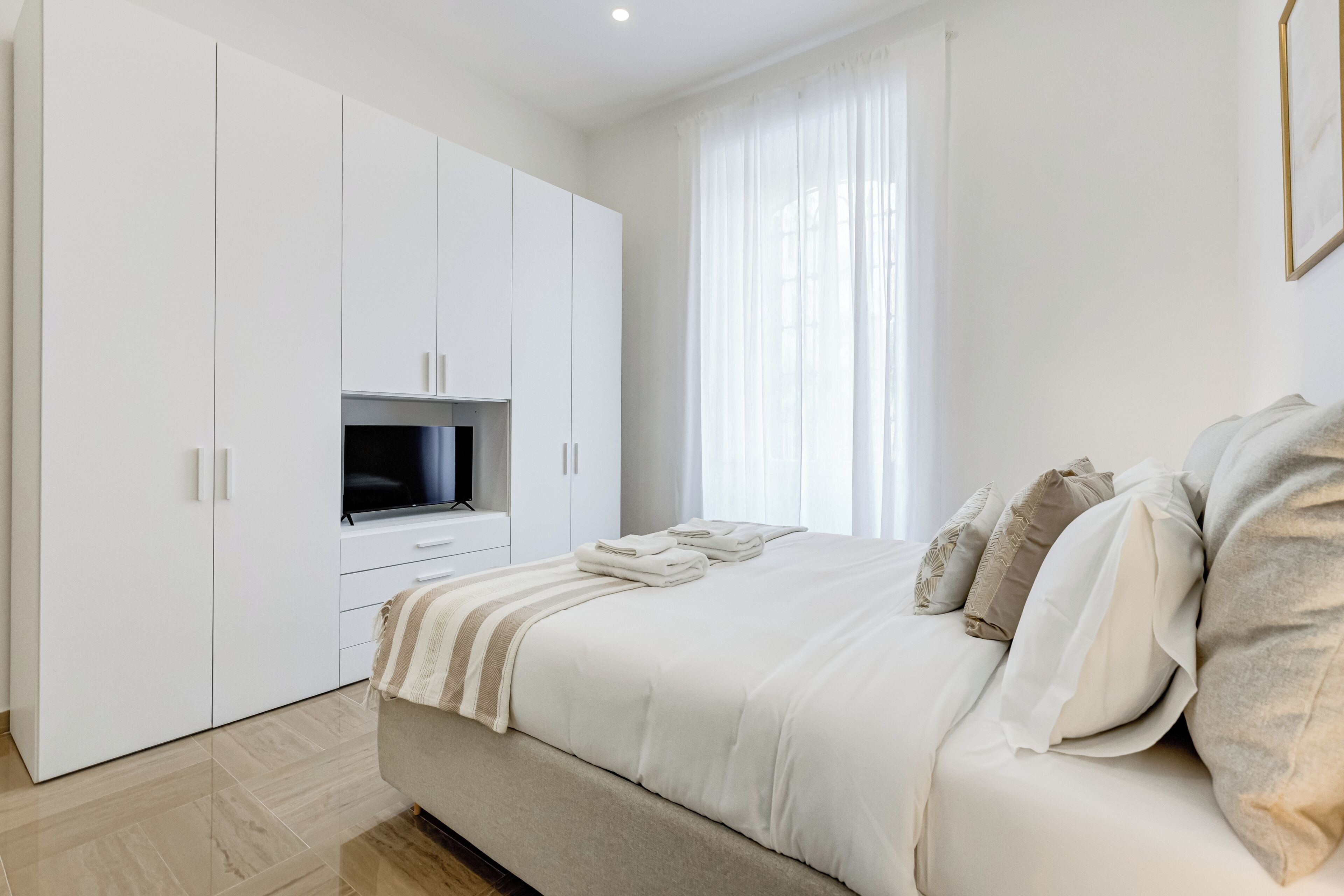 Un dormitorio moderno con cama, televisor y armario.