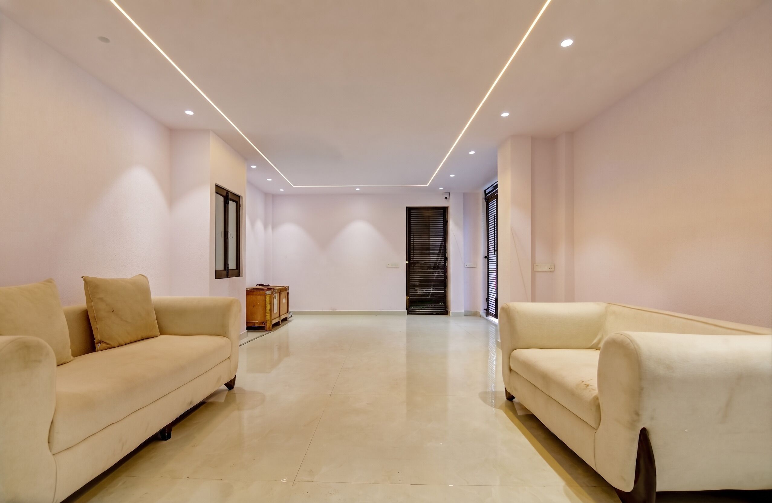 A spacious room with two sofas facing each other, a wooden cabinet, and a door with a window.