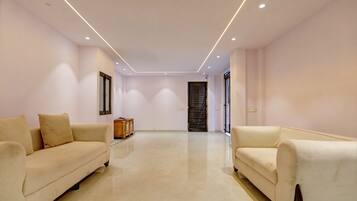 A spacious room with two sofas facing each other, a wooden cabinet, and a door with a window.