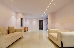 A spacious room with two sofas facing each other, a wooden cabinet, and a door with a window.