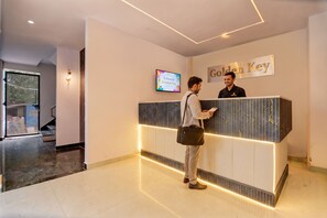 A reception desk with a 'Golden Key' sign, a digital welcome screen, and a modern interior design.