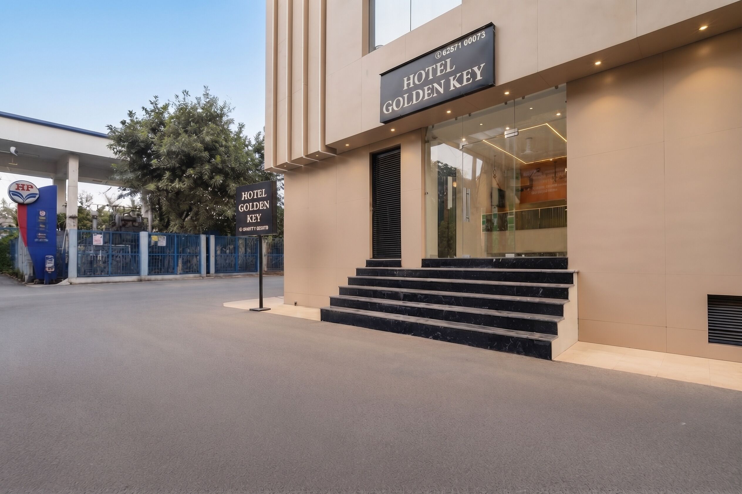 A modern hotel entrance with a sign reading 'HOTEL GOLDEN KEY' and a staircase leading to the entrance.