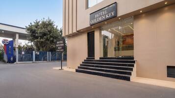 A modern hotel entrance with a sign reading 'HOTEL GOLDEN KEY' and a staircase leading to the entrance.