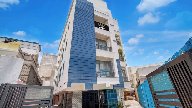 A multi-story building with a modern design, featuring a prominent vertical blue facade and a sign indicating a company service. - Super Collection O Queens  (Jaipur)