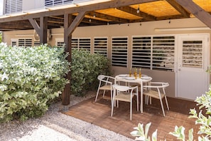 Eine Terrasse mit Tisch und Stühlen, umgeben von Pflanzen und einer Holzterrasse.