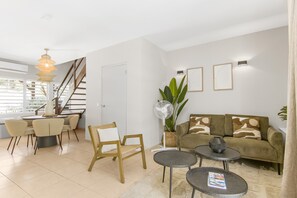 Ein modernes Wohnzimmer mit einer Couch, Sesseln, einem Esstisch und einer Treppe.