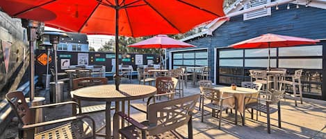 Une terrasse extérieure avec des tables et des chaises, des parasols rouges et un panneau indiquant la limite de vitesse.