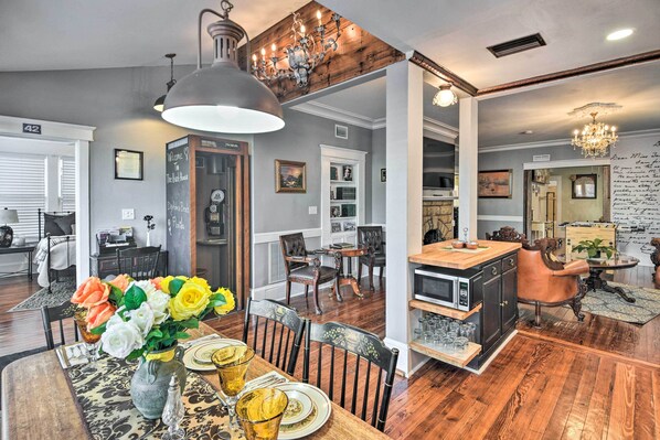 A dining area with a wooden table set for four, surrounded by dark wooden chairs. A chandelier hangs above the table, and a vase with flowers is on the table. - Daytona Beach 2-unit Combo Near Halifax River (Daytona Beach)