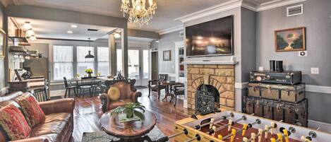 A spacious living room with a leather sofa, a foosball table, and a fireplace.