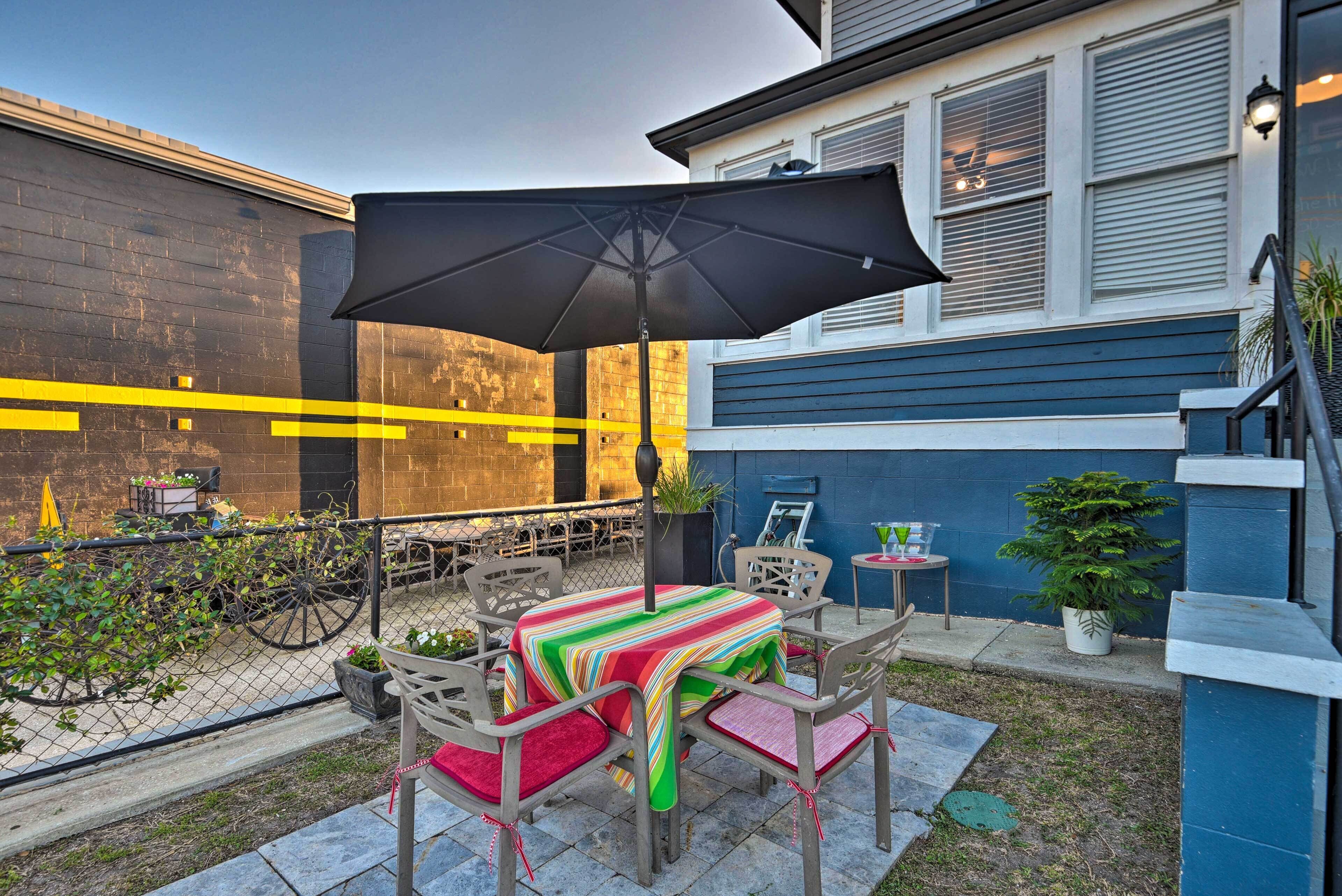 An outdoor patio with a table and chairs, a large umbrella, and a potted plant.