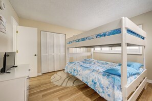A bunk bed with a blue and white patterned bedspread, a white desk with a computer, a closed white wardrobe, and a round rug on a wooden floor. - Majestic Gulf Views Condo w/ Balcony (Clearwater Beach)