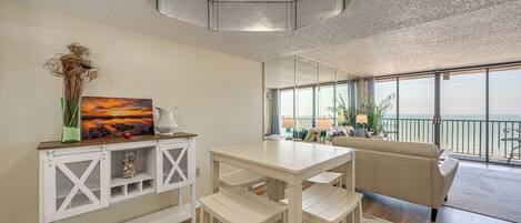 Ein modernes Wohnzimmer mit Essbereich, großen Fenstern und Meerblick.