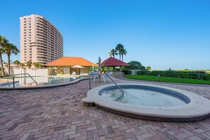 A hotel pool area with a hot tub, lounge chairs, and a building in the background. - Majestic Gulf Views Condo w/ Balcony (Clearwater Beach)