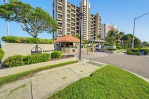 A residential building with a gated entrance, a small pavilion, and a well-maintained lawn. - Majestic Gulf Views Condo w/ Balcony (Clearwater Beach)