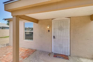 A building entrance with a metal door, a small window, and a welcome mat. - Room for 6 Cars on Balloon Fiesta Weekend (Albuquerque)