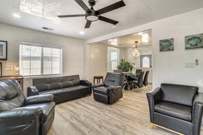A modern living room with a black leather sofa, a leather armchair, and a dining area with a table and chairs. - Room for 6 Cars on Balloon Fiesta Weekend (Albuquerque)
