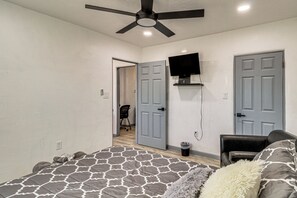 A bedroom with a bed, a ceiling fan, a TV mounted on the wall, and a door leading to another room. - Room for 6 Cars on Balloon Fiesta Weekend (Albuquerque)