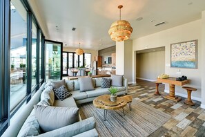 A modern living room with a sectional sofa, a coffee table, and a large window. - Steps to the Sand! Luxury Oceanside Pier Condo (Oceanside)