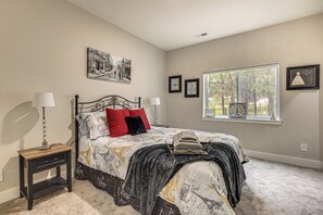 A bedroom with a bed, nightstands, a window with a view, and wall art. - Luxury Forest Retreat: Movie Room, Games, Hot Tub (Colorado Springs)