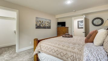 Quarto com cama, penteadeira, quadro, relógio e porta.