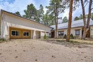 A modern building with a covered patio area, stone accents, and a gravel driveway. - Luxury Forest Retreat: Movie Room, Games, Hot Tub (Colorado Springs)