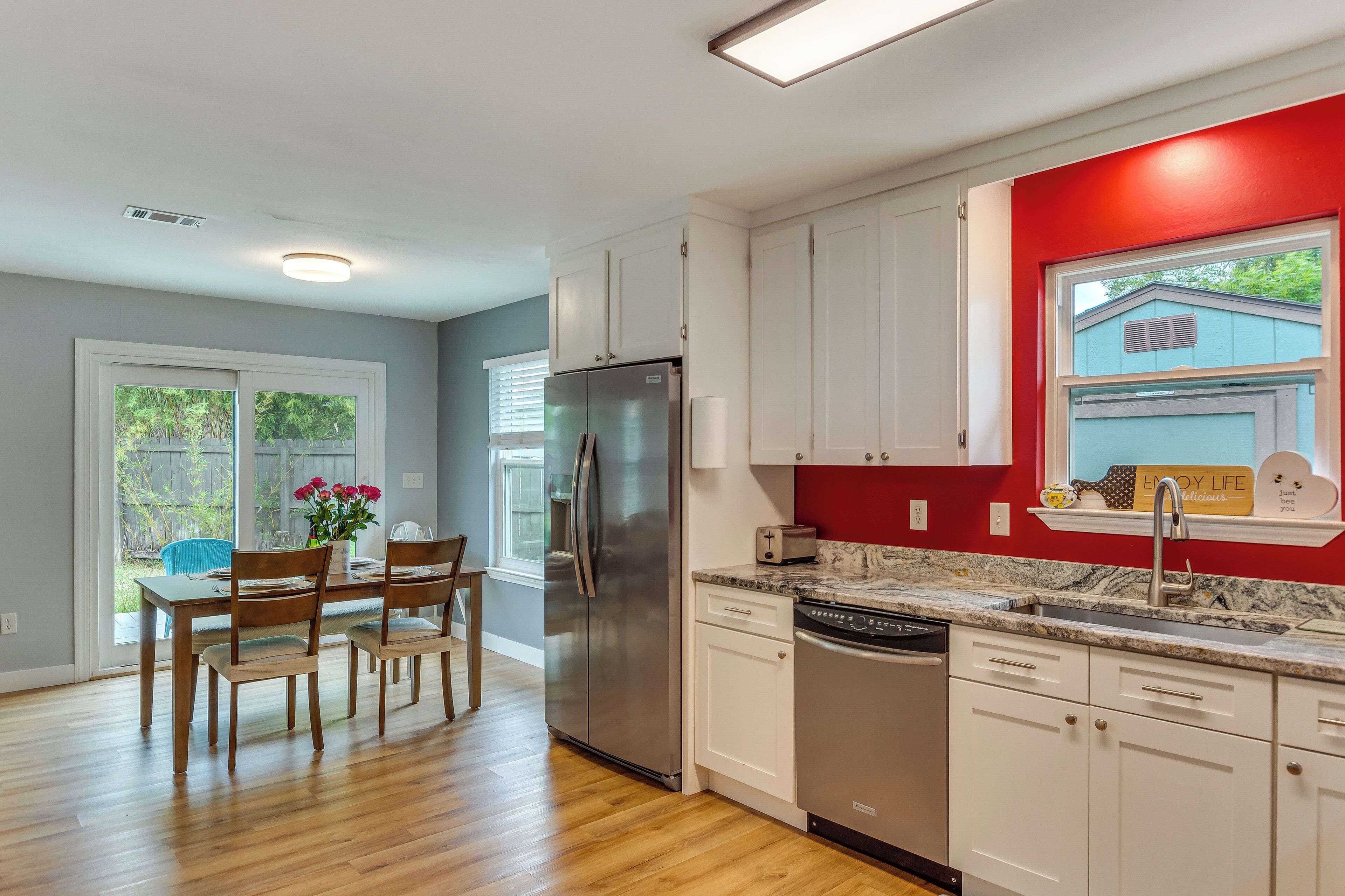A modern kitchen with white cabinets, a stainless steel refrigerator, and a granite countertop.