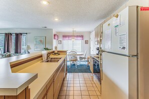 Eine kleine Küche mit Kühlschrank, Spüle und Essbereich.