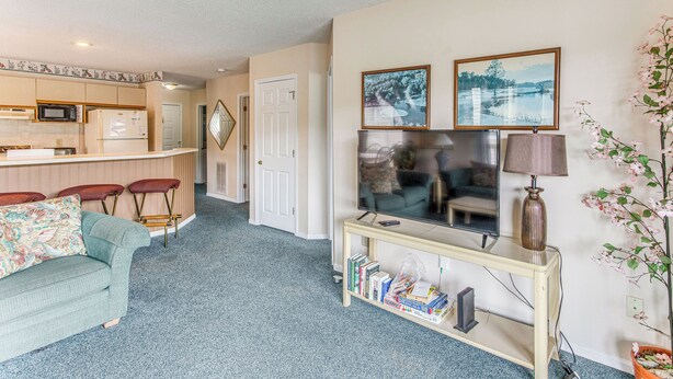 A living room with a television, a coffee table, and a sofa. There is a kitchen area with a microwave and a refrigerator. - Lake-view Balcony, Pool Access! Sunset Beach Condo (Sunset Beach)