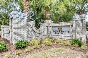 A brick wall with a sign for Oyster Pointe Sea Trail. - Lake-view Balcony, Pool Access! Sunset Beach Condo (Sunset Beach)