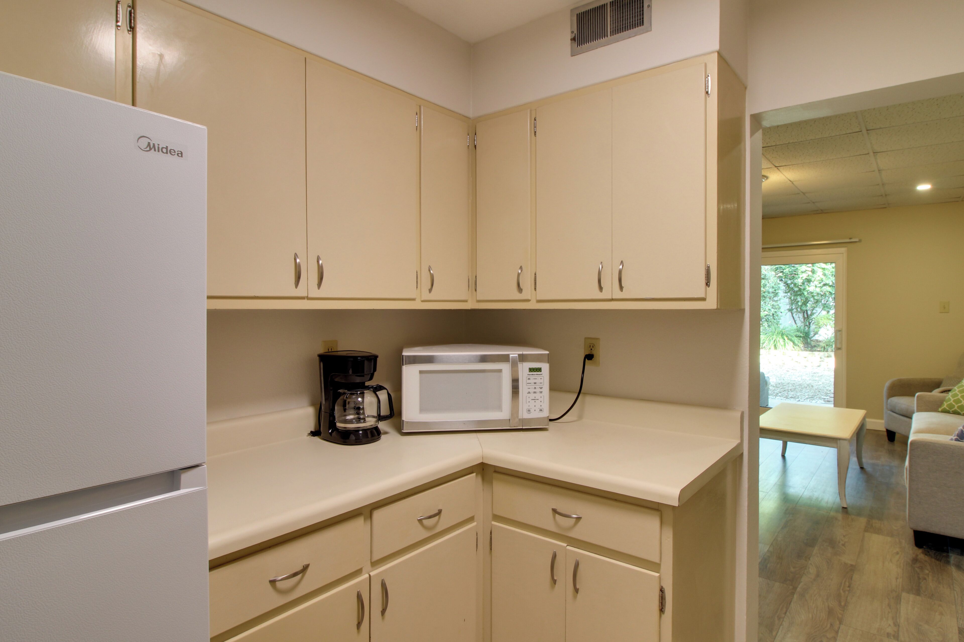 A kitchenette with a refrigerator, a coffee maker, and a microwave.