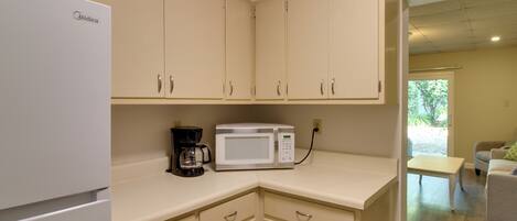 A kitchenette with a refrigerator, a coffee maker, and a microwave.