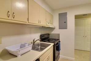 A kitchen with beige cabinets, a stainless steel sink, a stove, and a small window vent. - Private Patio, Yard! Townhome Near Pensacola Beach (Gulf Breeze)