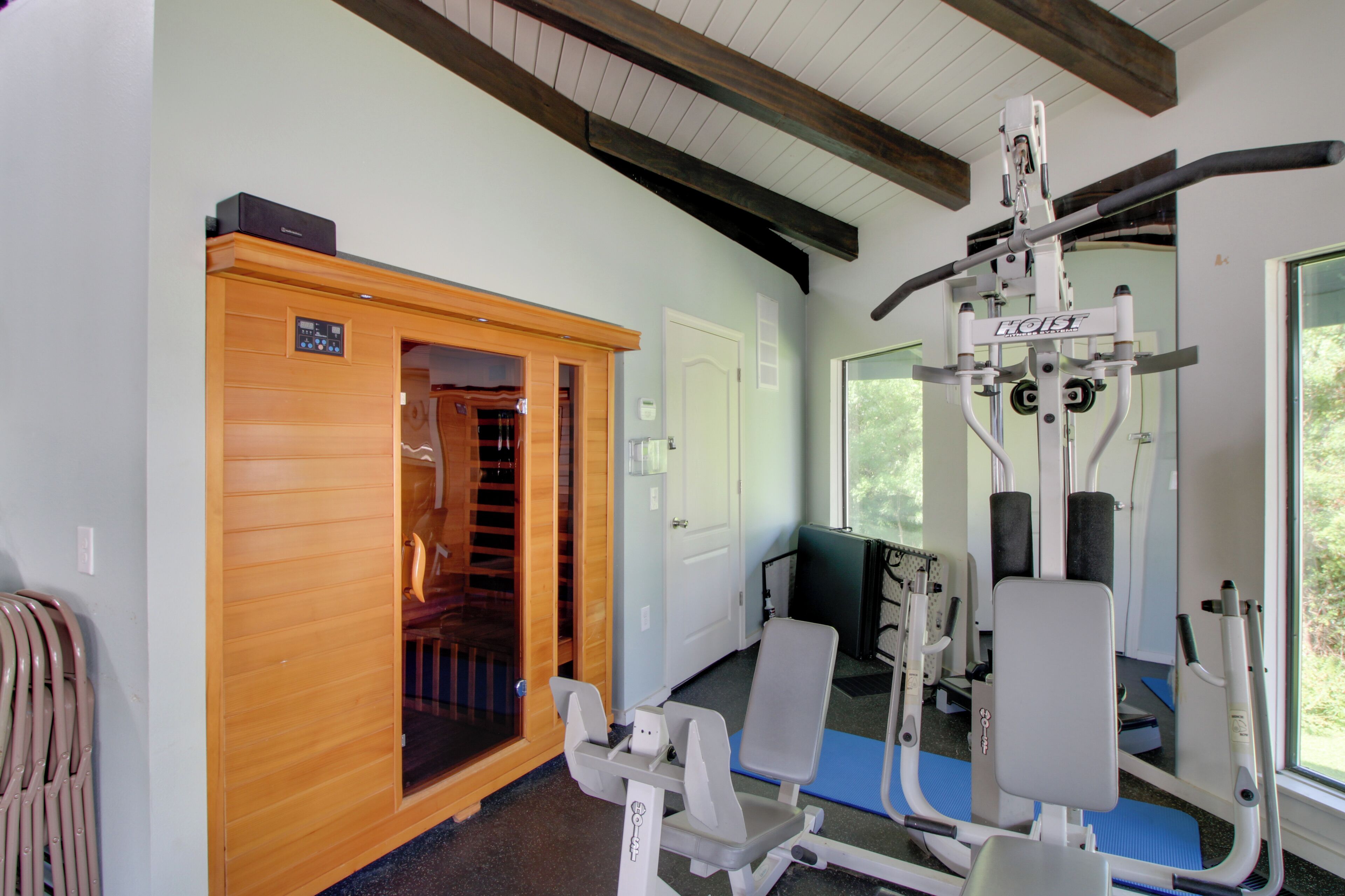 Une salle de sport équipée de matériel d’exercice, un sauna et une porte donnant sur une pièce.