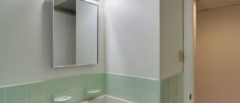 A bathroom with a white sink, a mirror, and a light fixture above it.