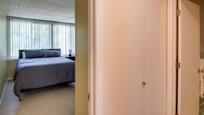 Ein Schlafzimmer mit einem Bett, einem Fenster mit Jalousien und einer Tür.