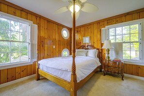 A four-poster bed with a canopy, a nightstand with a lamp, and a window with shutters. - Charming Waterfront Home With Mt Rainier View (Olympia)