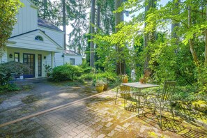A house with a paved driveway leading to a covered patio area with a table and chairs. - Charming Waterfront Home With Mt Rainier View (Olympia)