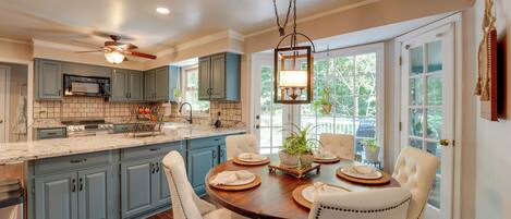 A kitchen with a central island, white chairs, and a dining table set for four.