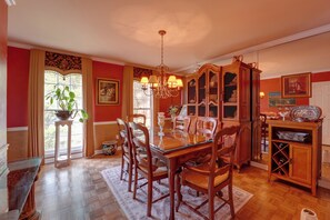 A dining room with a glass-top table, wooden chairs, a chandelier, and a cabinet with glass doors. - Group Getaway w/ Private Yard in Marietta (Marietta)