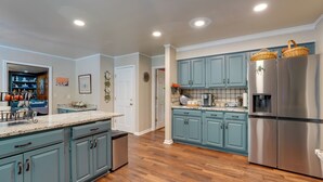 A modern kitchen with light blue cabinets, stainless steel appliances, and a wooden floor. - Group Getaway w/ Private Yard in Marietta (Marietta)