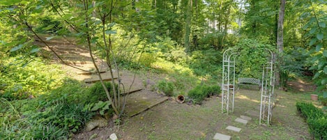 A garden with a wooden staircase, a metal trellis, and a variety of greenery.