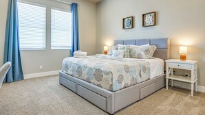 Un dormitorio con una cama, dos mesitas de noche, una lámpara y una ventana con cortinas.