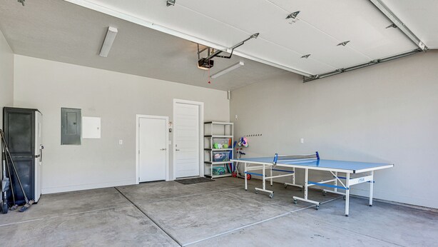 Una habitación amplia y limpia con mesa de ping pong, una puerta y una estantería con varios objetos.