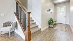 Una escalera con barandilla de madera y peldaños alfombrados, pared de color claro, una puerta con número y un pequeño estante con una bicicleta.